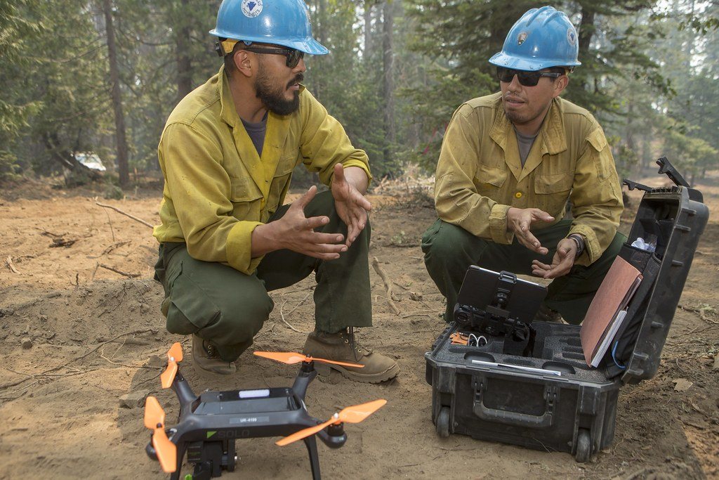 Two responders kneeling beside a drone and its case